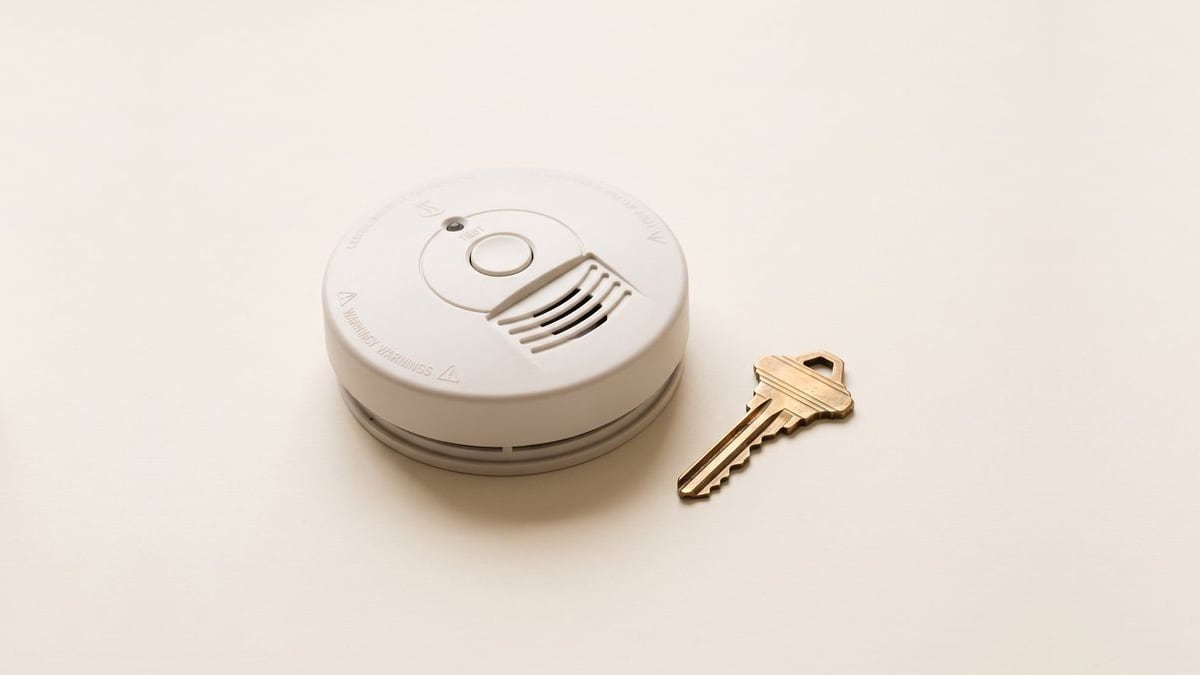 A smoke detector lying next to a house key